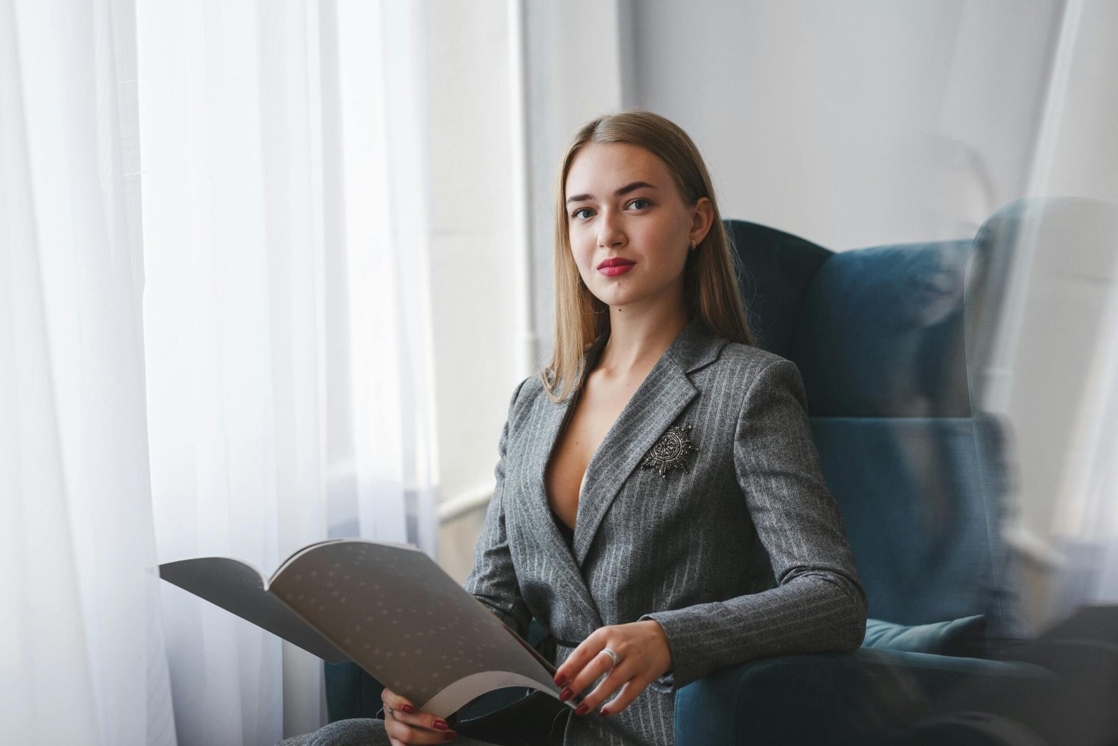 a woman sitting in a chair holding a magazine